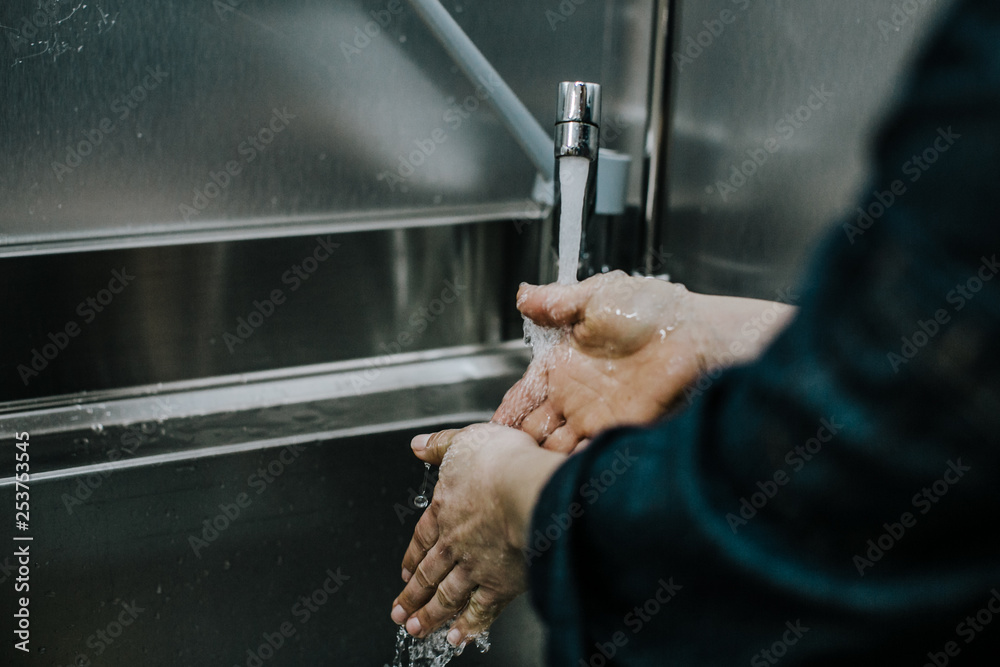© lubero - .Working woman cleaning her hands at the kitchen to prepare bread and buns at her bakery. Lifestyle. Work concept.