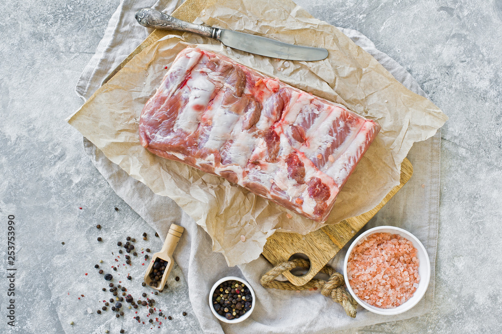 Raw pork ribs on a wooden chopping Board. Gray background, top view, space for text