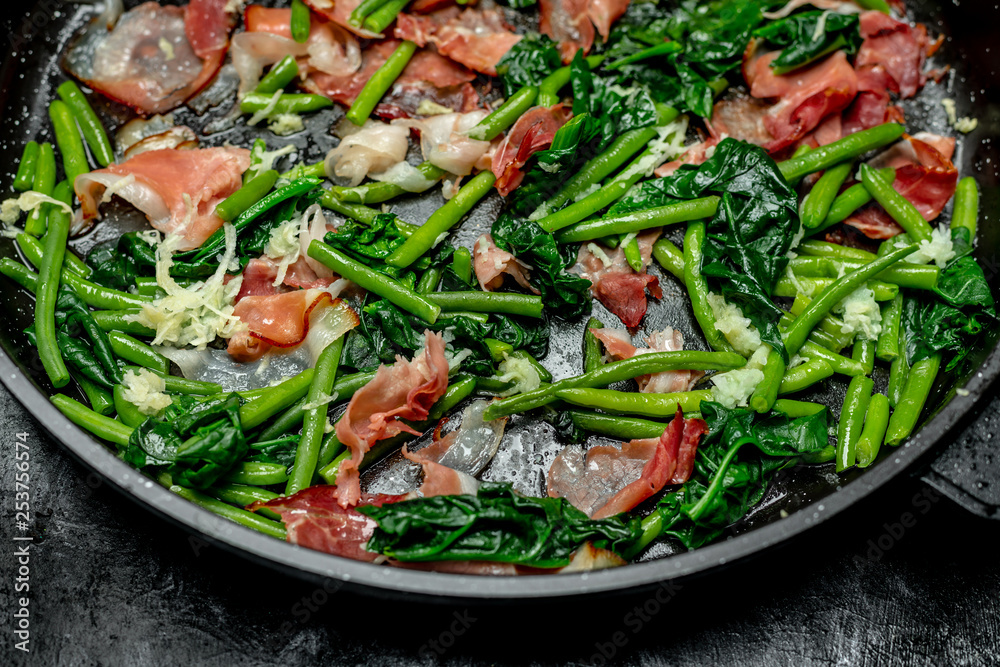 Peas sprouts, young spinach leaves fried in a pan together with a crispy, bacon-flavored