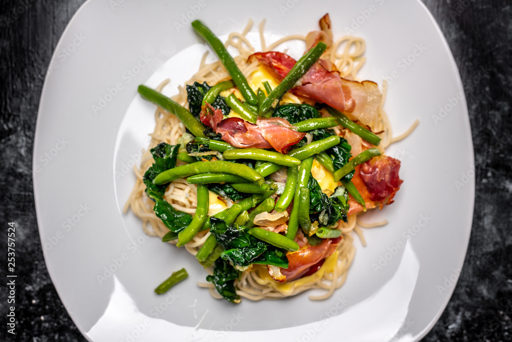 Spaghetti carbonara with pieces of crispy bacon, garlic, fresh spinach leaves and sprouts of green, young peas Spaghetti carbonara with pieces of crispy bacon, garlic, fresh spinach leaves and sprouts of green, young peas