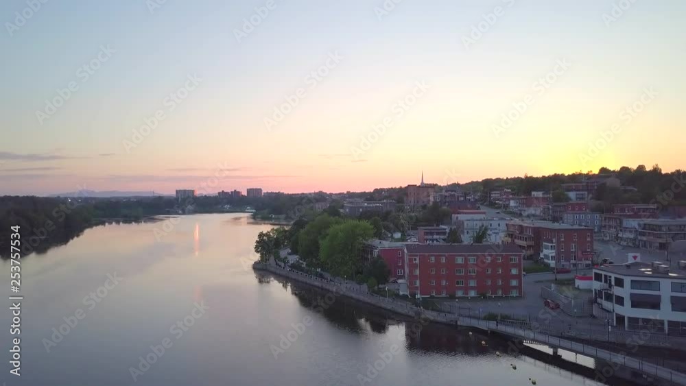 Drone flying up near downtown on a small city during sunset, over the lake, with buildings, cars passing by and pedrestians wandering - summer season beautiful landscape. Drone flying up near downtown on a small city during sunset, over the lake, with buildings, cars passing by and pedrestians wandering - summer season beautiful landscape.