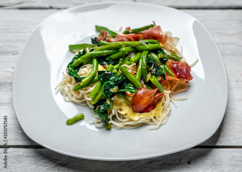 Spaghetti carbonara with pieces of crispy bacon, garlic, fresh spinach leaves and sprouts of green, young peas Spaghetti carbonara with pieces of crispy bacon, garlic, fresh spinach leaves and sprouts of green, young peas
