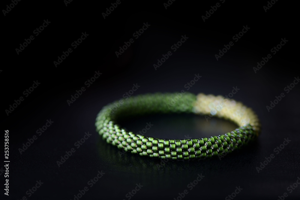 Bead crochet bracelet two shades of green on a dark background close up Bead crochet bracelet two shades of green on a dark background close up