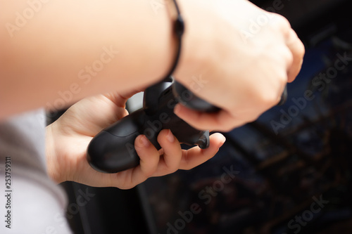 Female hands hold joystick  a young girl plays a video game