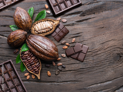 Cocoa pod, cocoa beans and chocolate on the wooden table. Top view.