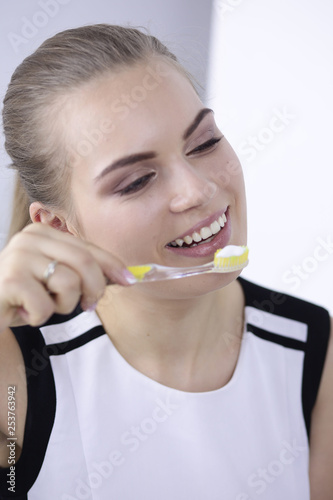 Smiling young woman with healthy teeth brushing her teeth