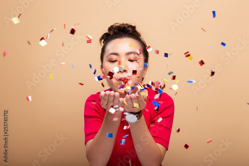 Portrait of a cheerful woman with confetti rain and celebrating isolated over background