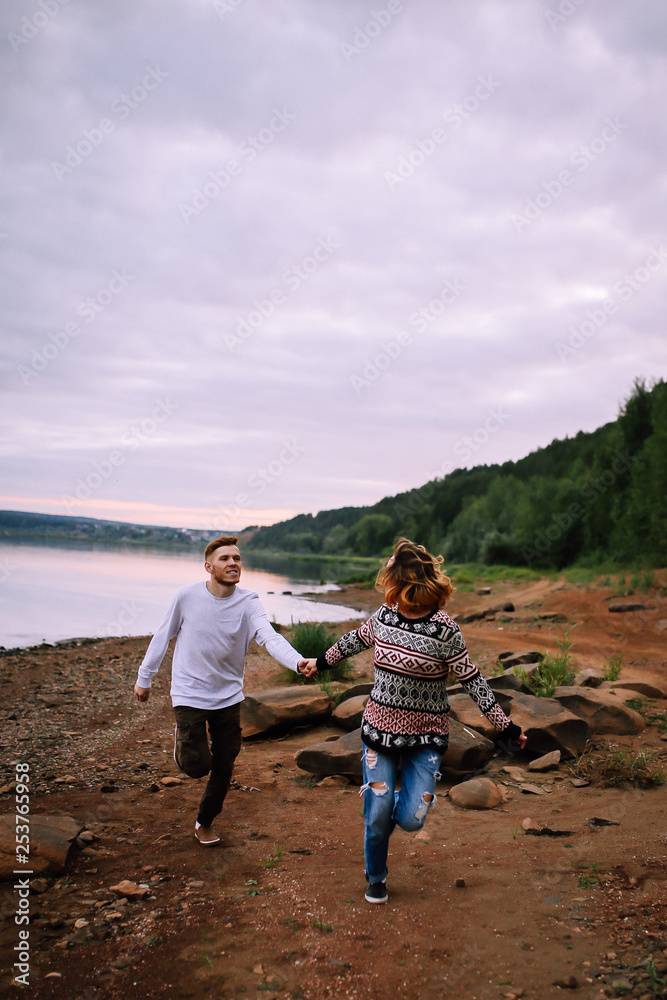 Young couple having fun and running along the river Young couple having fun and running along the river