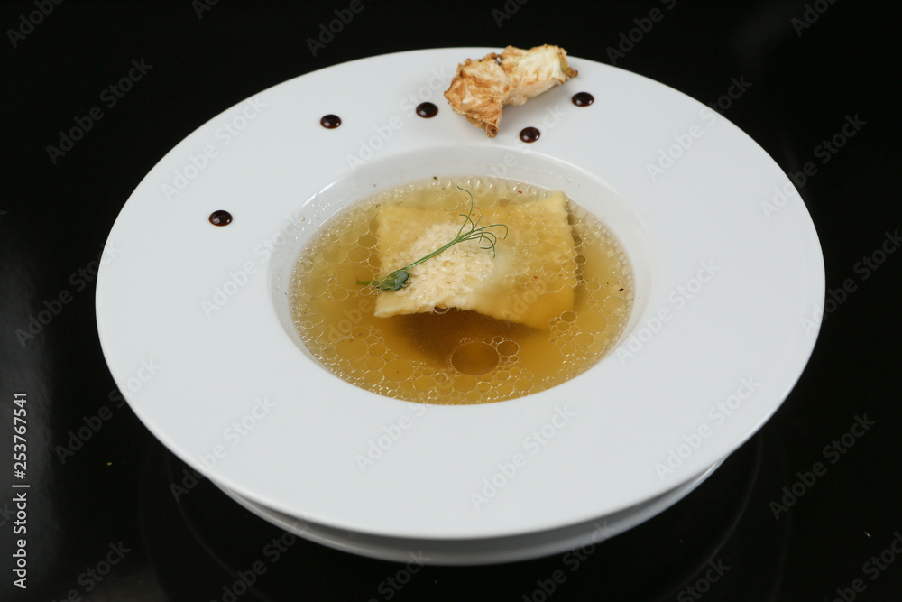 Minimalistic serving of food, white transparent chicken broth in a plate of rice, cheese and dumplings, decorated Minimalistic serving of food, white transparent chicken broth in a plate of rice, cheese and dumplings, decorated