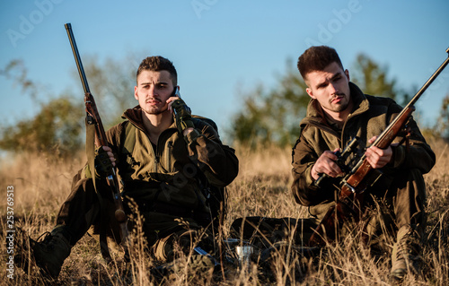 Rest for real men concept. Hunters with rifles relaxing in nature environment. Hunting with friends hobby leisure. Hunters satisfied with catch drink warming beverage. Hunters friends enjoy leisure