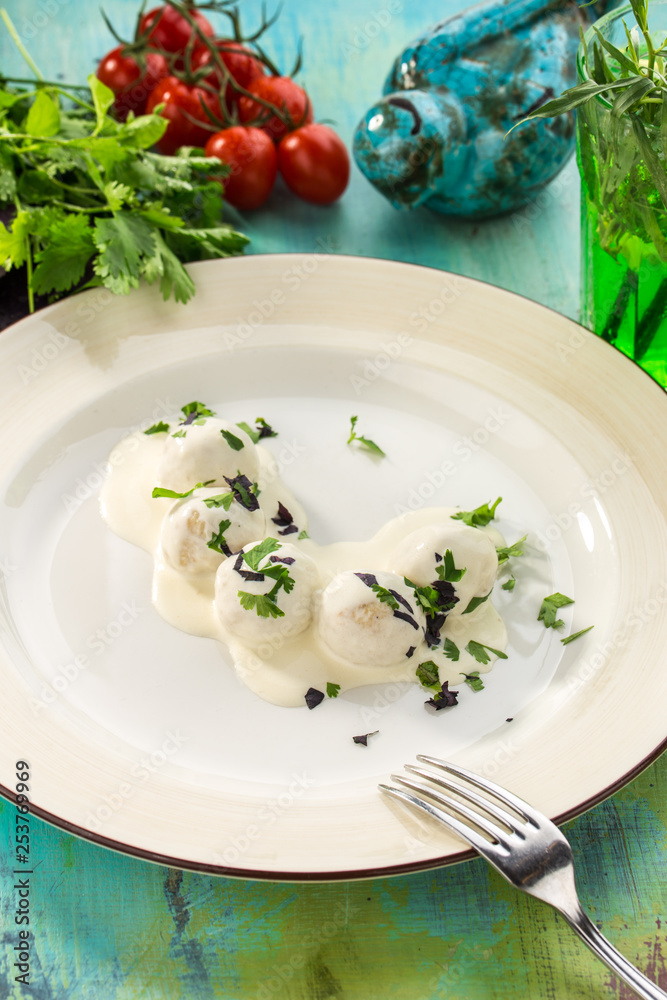 Meatball in white sauce bechamel on blue wooden table Meatball in white sauce bechamel on blue wooden table