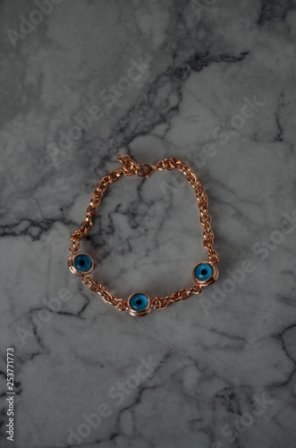 Gold rose bracelet with evil eye bead symbol on white background