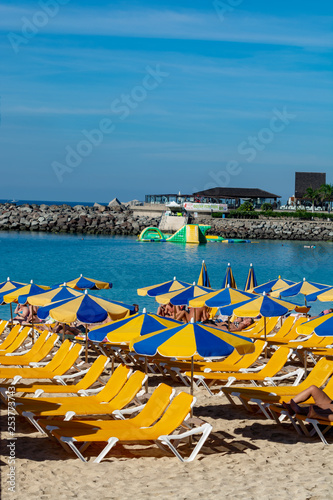 Crowded beach with sun umbrellas and chairs waiting for tourists, paid service on beaches