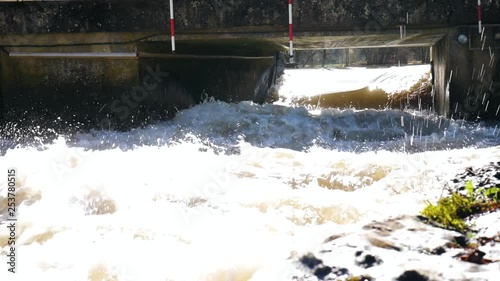 A turbulent river under the bridge with hanging striped gates for kayakers to practice slalom. photo