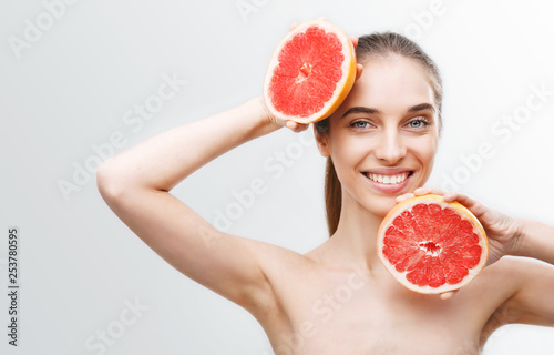 Image of excited cute young woman isolated over white wall background holding grapefruit photo