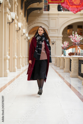 Beautiful girl in stylish in a long burgundy coat, indoor shop © Andrey_Arkusha