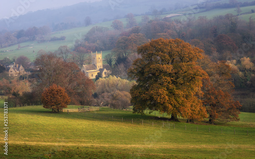 Cotswolds St. Eadburgha's Church in Autumn nestled in early morning sunlight