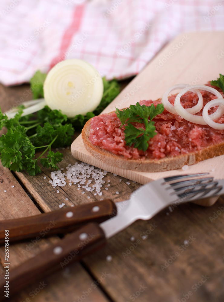 slice of bread with minced meat, parsley and onions - on rustic wooden table - breakfast bread - pork mett slice of bread with minced meat, parsley and onions - on rustic wooden table - breakfast bread - pork mett