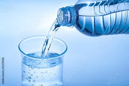 Water poured into the glass. Crystal drink water on light blue background