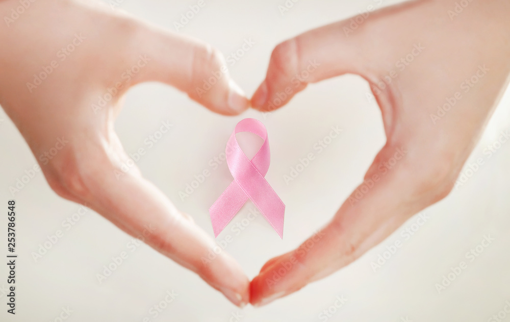 Obraz premium Hands making a heart shape with a pink ribbon, breast cancer awareness concept