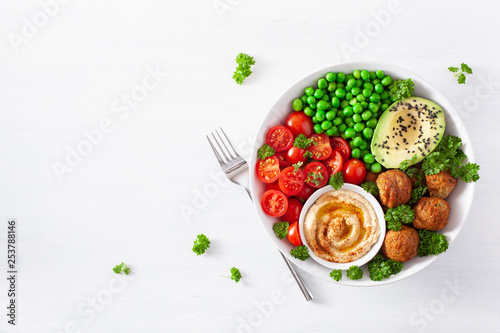 healthy vegan lunch bowl with falafel hummus tomato avocado peas