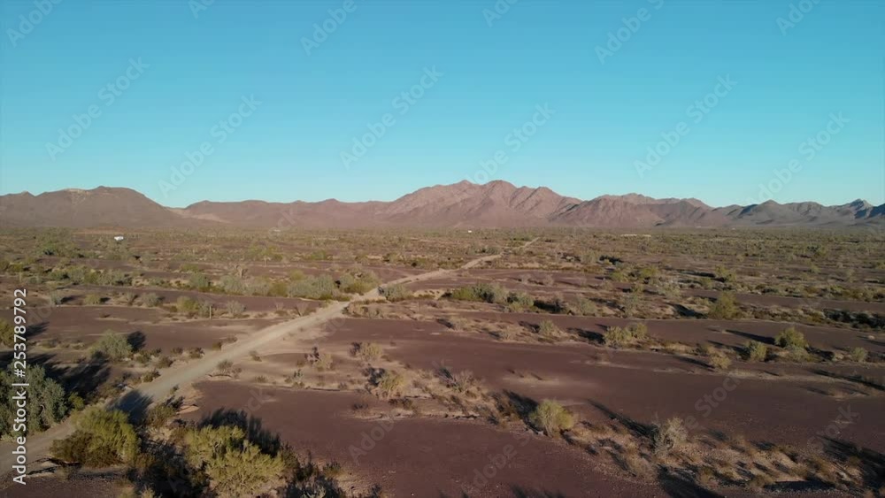 Slow Cinematic Flight Down Over A Dirt Road With Mountains On The Horizon During The Day From An Aerial Drone Slow Cinematic Flight Down Over A Dirt Road With Mountains On The Horizon During The Day From An Aerial Drone