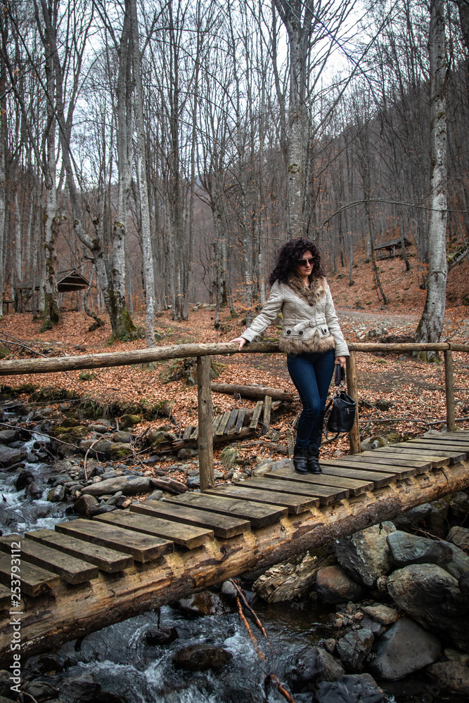 Woman stands on small wooden bridge on creek in the forest Woman stands on small wooden bridge on creek in the forest