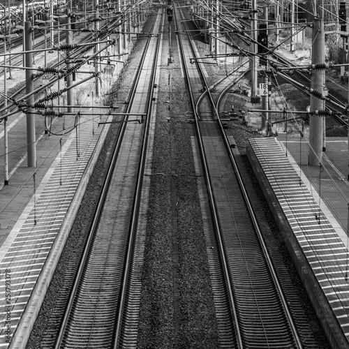 Perspective view of railway tracks with overhead lines next to a platform