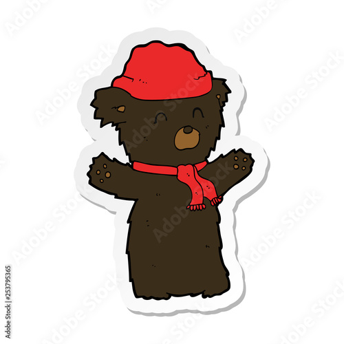 sticker of a cartooon cute black bear in hat and scarf