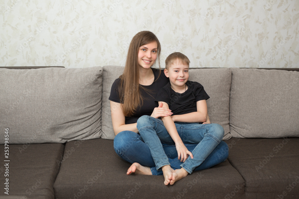 beautiful young mother with her son on the couch in the home interior