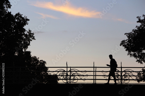 silhouette of young man passing on an old bridge