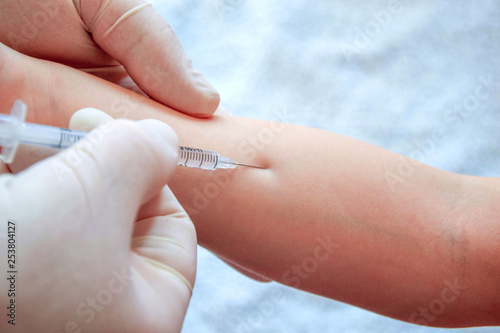 Hand with syringe for injection. Vaccination against influenza and virus. Insulin syringe with thin needle. The baby is ready for vaccination.