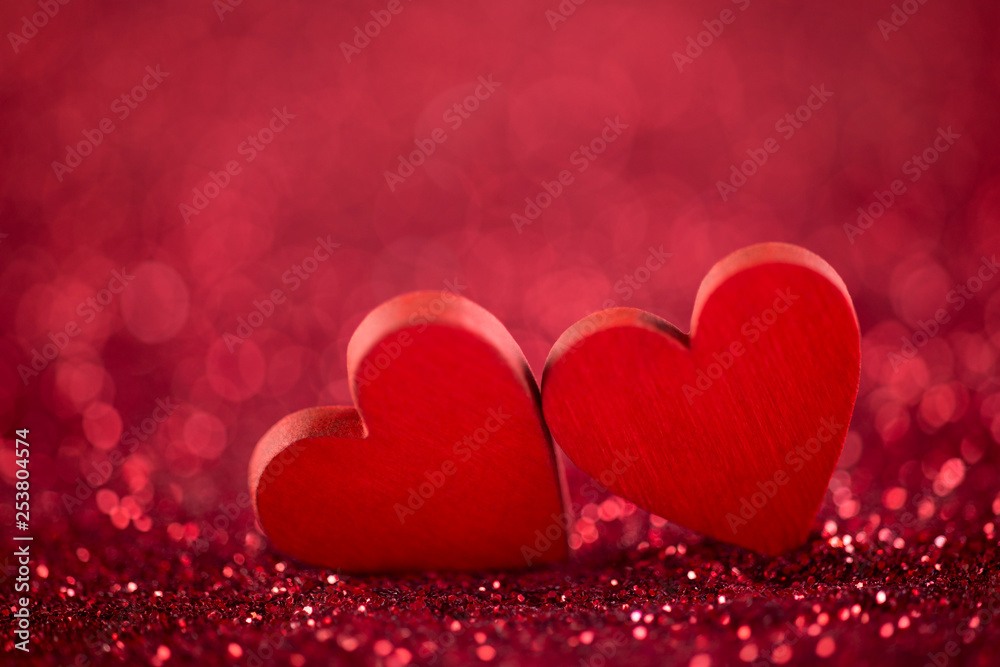Two red hearts on glitter background in love concept 