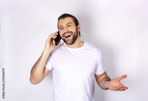 Handsome man in white t-shirt over white background smiling talking on phone
