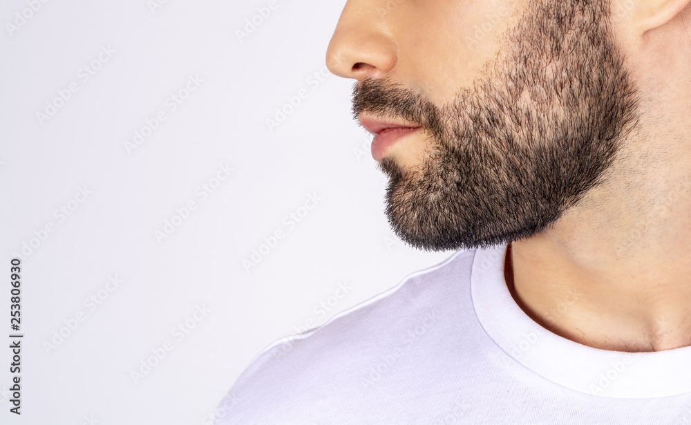 Obraz premium Handsome man in white t-shirt on a white background smiling, looking away, profile, close-up