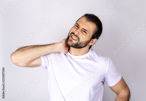 Handsome man in white t-shirt on white background, neck hurts