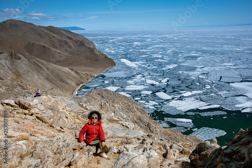 View above big beautiful lake Baikal with Ice floes floating on the water with girl wears red jacket, Russia