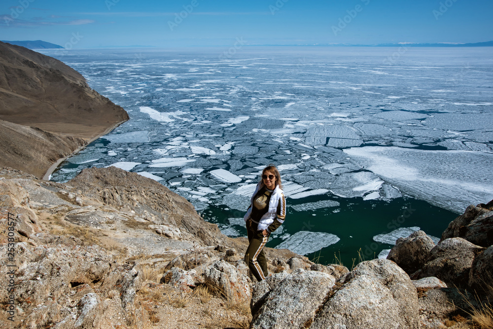 View above big beautiful lake Baikal with Ice floes floating on the water with girl wears white jacket, Russia