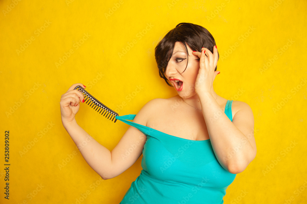 cute happy smiling girl with short black hair with bangs have fun with a comb on yellow solid Studio background with space cute happy smiling girl with short black hair with bangs have fun with a comb on yellow solid Studio background with space