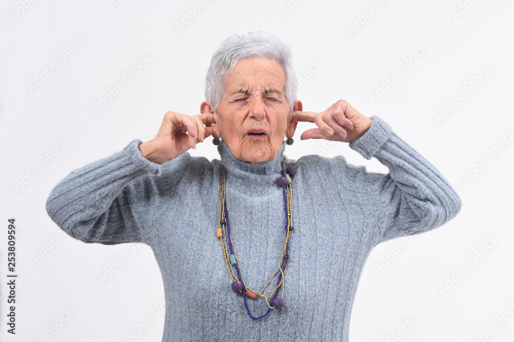 senior woman making noise hurting her ears on white background senior woman making noise hurting her ears on white background