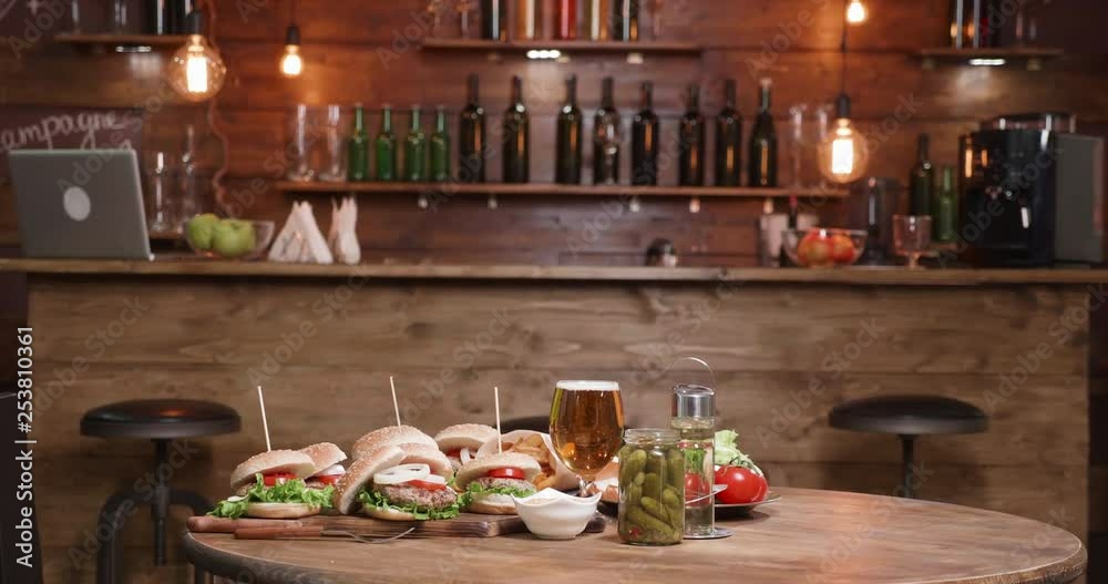 Fresh homemade burgers are ready on a restaurant table in front of the bar. Nice looking hamburgers on a wooden table. Fresh homemade burgers are ready on a restaurant table in front of the bar. Nice looking hamburgers on a wooden table.
