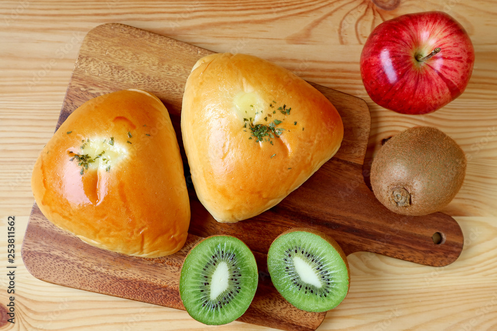 Top view of savory buns on wooden tray with apple and kiwi fruits Top view of savory buns on wooden tray with apple and kiwi fruits