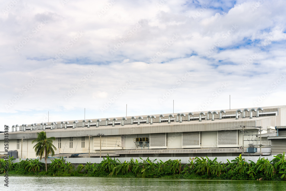 Naklejka premium Many ventilation chimneys on the factory roof at blue sky and clouds with copy space