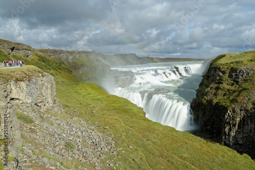 Touristen betrachten den Regenbogen über dem Wasserfall Gullfoss, Island