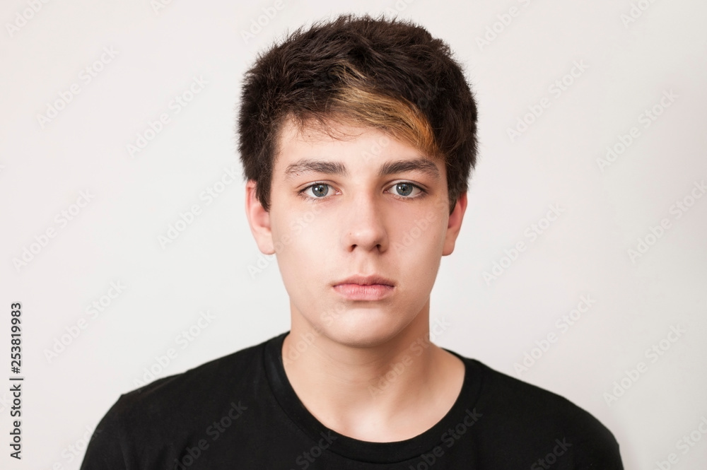 A beautiful but sad boy in a black shirt on a light background. The boy has painted hair and beautiful eyes A beautiful but sad boy in a black shirt on a light background. The boy has painted hair and beautiful eyes