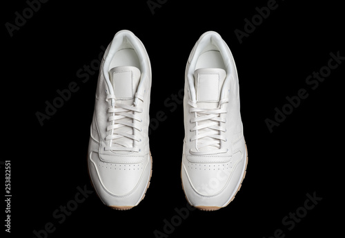 pair of white sneakers isolated on black background