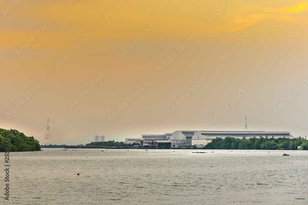 large industrial factory building side coast of sea or river in evening and soft orange sunshine