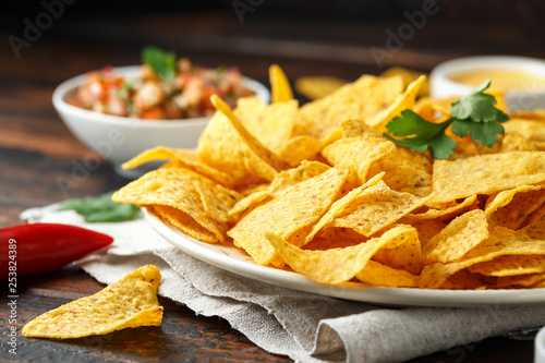 Tortilla nachos chips with cheese sauce, guacamole and tomatoes salsa dip. lime. chilli pepper.