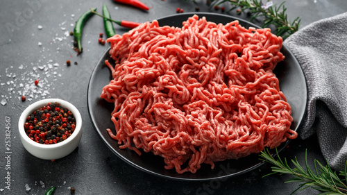 Tableau sur toile Fresh Raw mince, Minced beef, ground meat with herbs and spices on black plate
