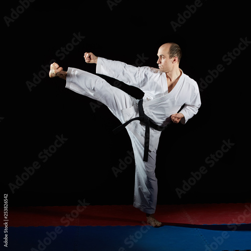 Black belt athlete doing formal karate exercises on red and blue tatami